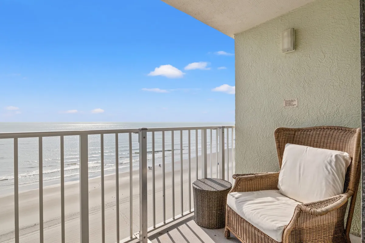 A serene private balcony with a wicker chair overlooking the vast Atlantic Ocean. The sky glows with clouds, and the space is ideal for enjoying a sunrise coffee or unwinding to the sound of waves at sunset.