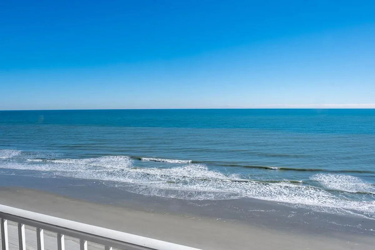 A breathtaking view of the beach, featuring gentle ocean waves, a sandy shoreline, and a clear blue sky. The tranquil scene invites thoughts of morning strolls, sandcastle building, or simply basking in the sun, perfectly echoing the direct beach access mentioned in the section.